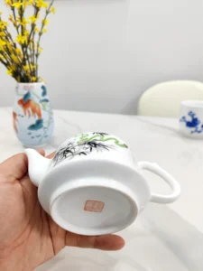 Red artist signature and seal on teapot base, highlighting handmade authenticity